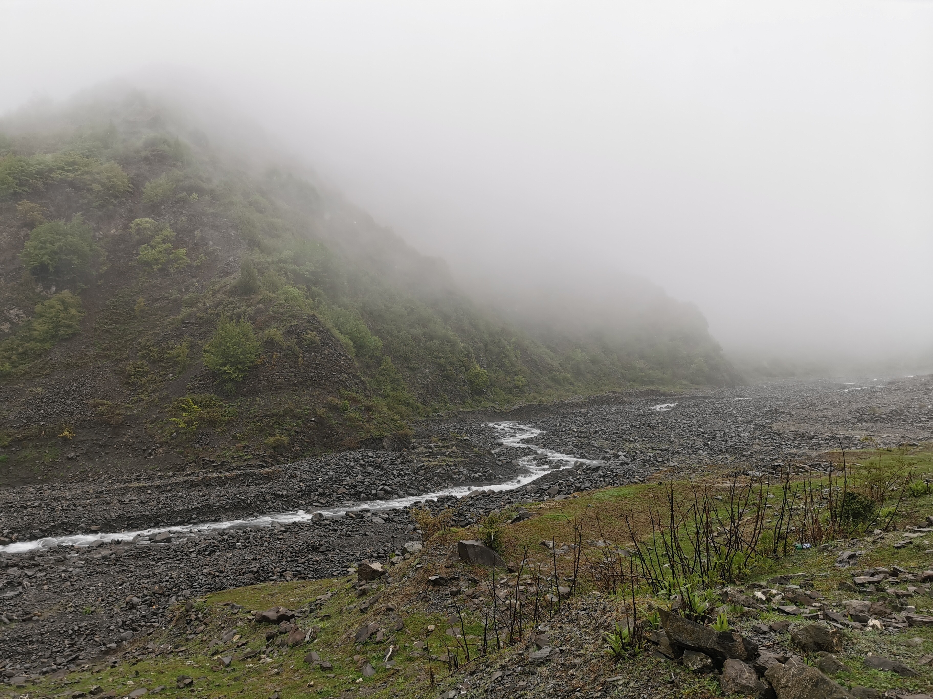 Rzeka Kurmukczay - Ilisu Widok na rzekę Kurmukczay w Ilisu, mgły i chmury deszczowe okrywają wznoszące się obok rzeki góry.
